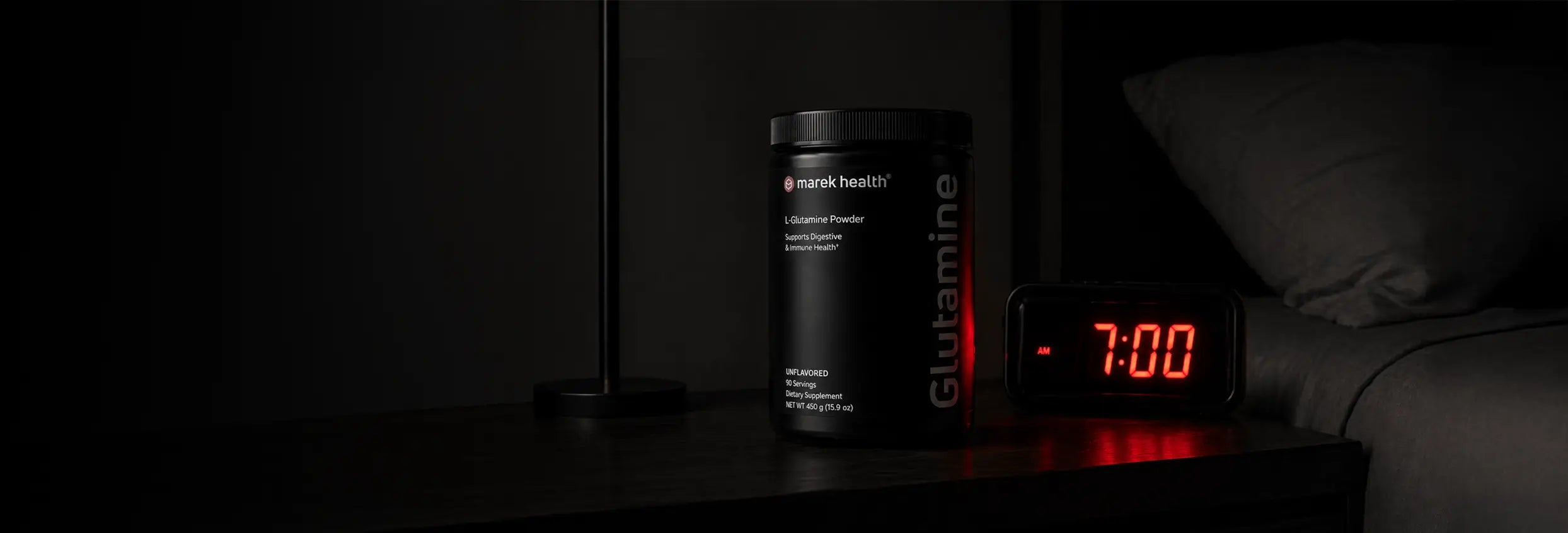 Marek Health L-Glutamine Powder supplement on bedside nightstand with alarm clock, dark ambient bedroom scene